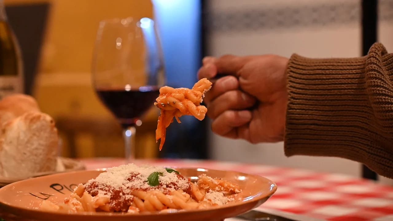 Pasta recién servida y una copa de vino en la mesa de La Piccola