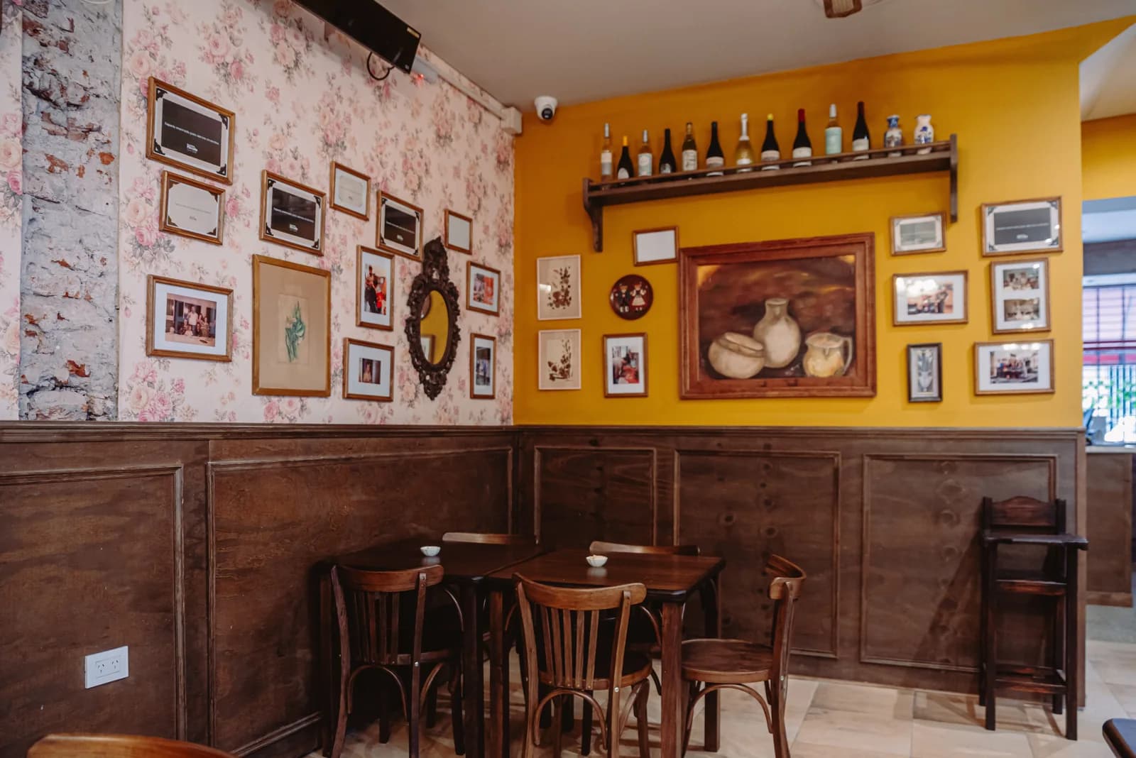 El salón de La Piccola, con paredes amarillas, cuadros y mesas de madera